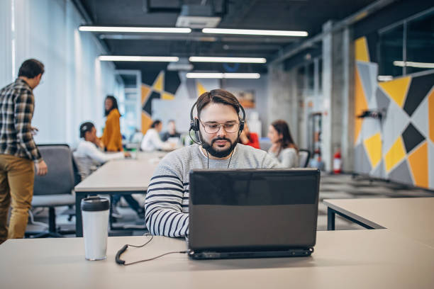 istock Young man working on laptop in big modern office 1249226950