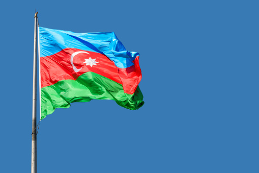 Flag of Azerbaijan against blue sky on a sunny day.