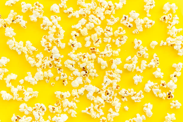 istock Popcorn scattered on yellow background top view 1249228829