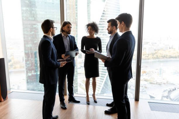 istock Diverse businesspeople standing in modern office, discussing project 1249232588