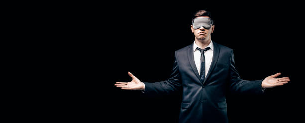 Portrait of a man in a mask for sleeping. He stands against a black wall. Blind business concept. Work during the crisis. stock photo