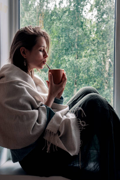 istock girl drinks mate on the windowsill by the window 1249246203