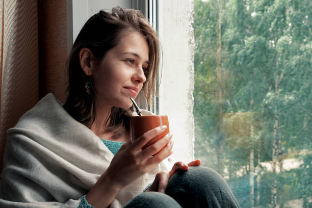 istock girl drinks mate on the windowsill by the window 1249246296