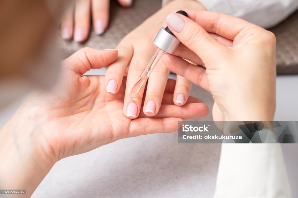 Manikiurzystka wylewa olej na paznokcie kobiety - Zbiór zdjęć royalty-free (Olejek eteryczny)