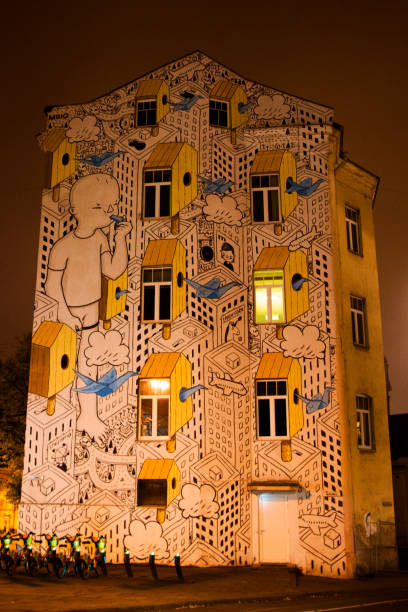 VILNIUS, LITHUANIA - OCTOBER 17, 2017: Mural on the building exterior, night and yellow lights. Windows and wall. Old famous building.