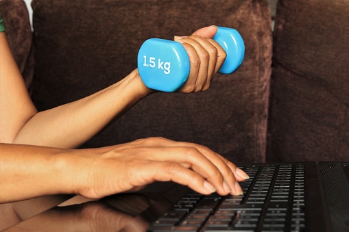 Woman hands doing exercise and using computer in the same time. photo