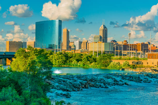 The White River flows along side of  Indianapolis, Indiana The cascading White River and the skyline of Indianapolis, Indiana both glow in the last light of the day. landscape view of indianapolis indiana during the day stock pictures, royalty-free photos & images