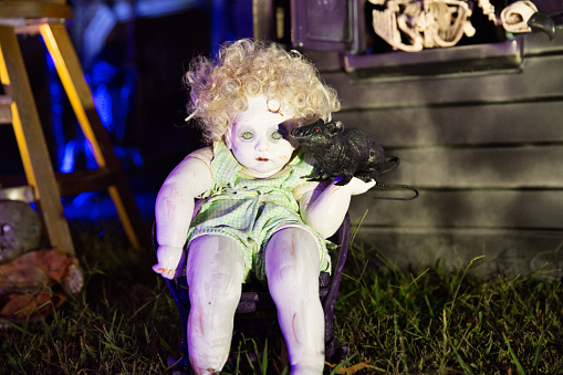 DIY Halloween doll holding pretend rat in creative yard of Halloween decorations