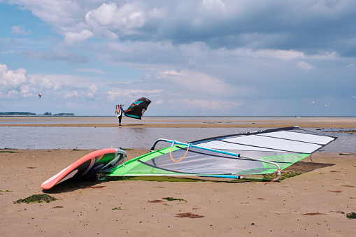 windsurfer board in the foreground with kitesurfing in the background.