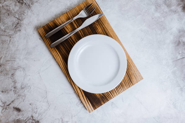 istock Empty white plate on a wooden board with cutlery. 1249259875