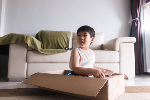 istock Elementary age boy in cardboard box to pretends to drive 1249260105