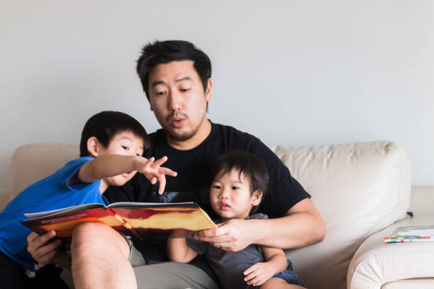 jovem aponta para livro de história pai está lendo em voz alta - stay at home dad - fotografias e filmes do acervo