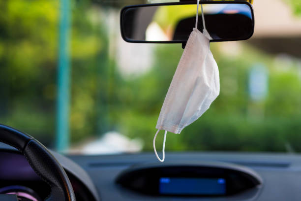 istock Face mask hung in car's rear-view mirror 1249260188