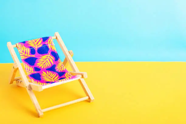 Photo of Beach chair on the yellow ground with blue background.