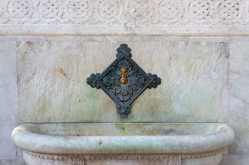 Old historical iron street fountain on marble wall