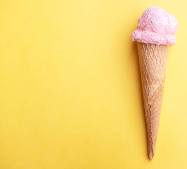 istock Close up strawberry ice cream in waffles cone on yellow background. Copy space. 1249263335