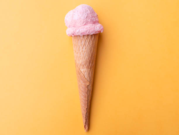 istock Close up strawberry ice cream in waffles cone on orange background. Copy space. 1249263907