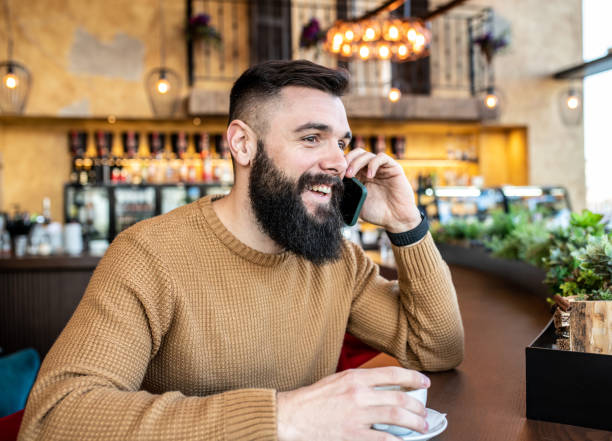 istock A young man talking on a phone in a cafe, smiling. 1249265819