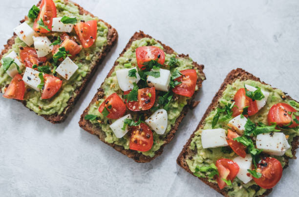 Bruschetta toast with guacamole and tomatoes. Bruschetta toast with guacamole and tomatoes, sea salt and herbs on dark bread, healthy nutrition. Close up. High quality photo egg cherry tomato rye stock pictures, royalty-free photos & images