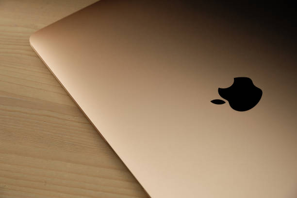 brand new gold macbook air (2020) on a wooden table. - macbook apple macintosh laptop apple computers imagens e fotografias de stock