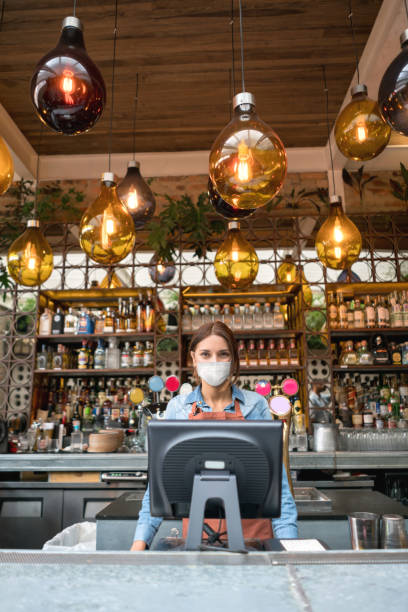 istock Waitress working at a restaurant behind the counter wearing a facemask during the COVID-19 pandemic 1249276390
