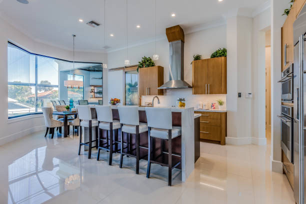 White flooring and brown wood cabinets in luxury Florida home Amenities in new kitchen include pull down faucet and pendant lighting bar stool photos stock pictures, royalty-free photos & images