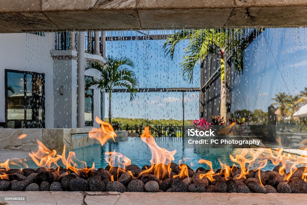 Unique firepit poolside with waterfall Look through firepit Fire Pit Stock Photo