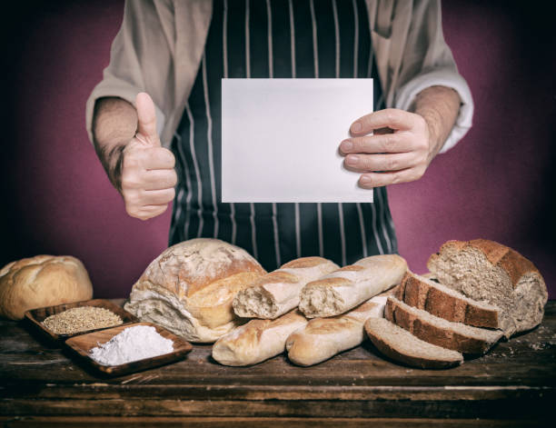 istock Baker holding empty sign at bakery and bread on wooden table 1249280578