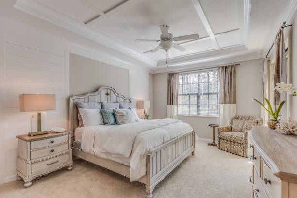 Beautifully decorated master bedroom with white and light brown tones Ceiling fan and coffered ceiling are examples of decorative additions to this bedroom chest furniture stock pictures, royalty-free photos & images
