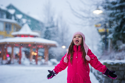 Girl playing in the snow in Whistler village. Winter vacations in British Columbia. Childhood memories from winter holidays.