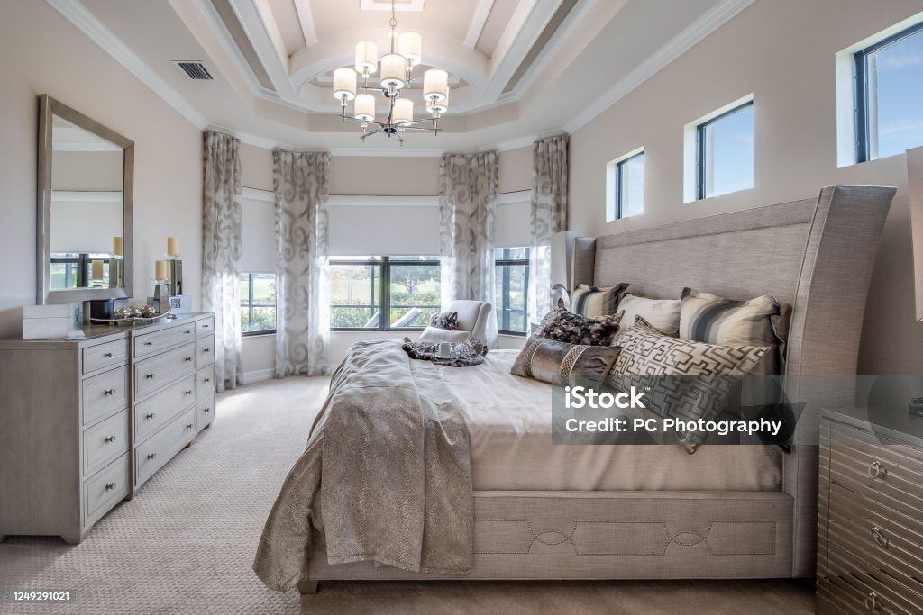 Beautiful bedroom with gray furniture Many luxuries such as chandelier, coffered ceiling and reading nook in master bedroom Luxury Stock Photo
