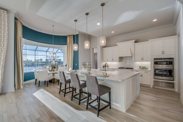 Spacious white kitchen Amenities in new kitchen include double oven, wood floor and pendant lighting bar stool photos stock pictures, royalty-free photos & images