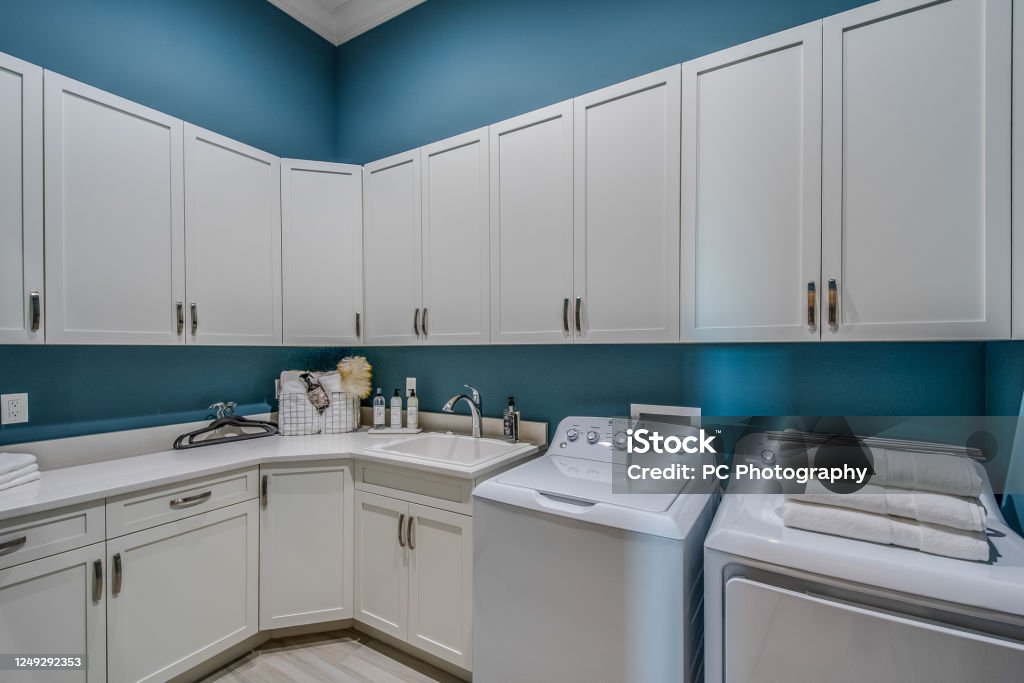 Laundry room with white cabinets and blue painted walls Many cabinets for storage and supplies in utility room Utility Room Stock Photo