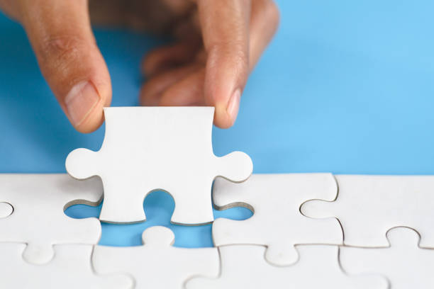 istock White jigsaw in the hands of humans, The correct solution. Teamwork, Solving and completing the task. Last piece of jigsaw puzzle. Assembling  jigsaw puzzle pieces. 1249309058