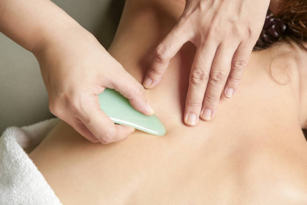 gua sha behandlung - traditionelle heiltechnik - massaging spa treatment stone massage therapist stock-fotos und bilder