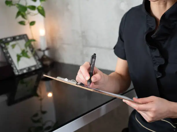 An esthetician in a black uniform who fills in a medical record at an esthetic salon