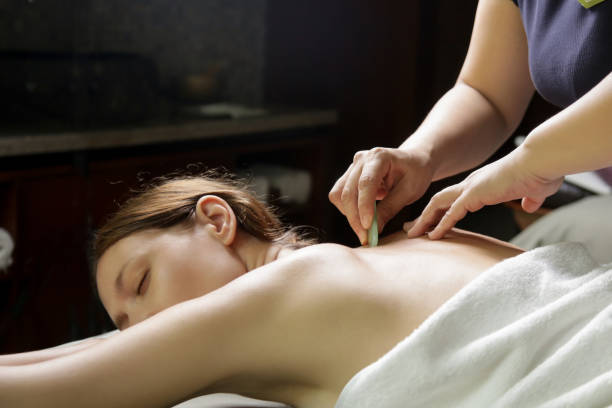 gua sha behandlung - traditionelle heiltechnik - massaging spa treatment stone massage therapist stock-fotos und bilder