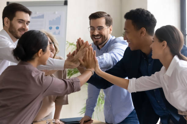 Diverse workers coach giving high five at company meeting. Diverse workers coach giving high five at company meeting. Happy multiracial colleagues with indian and black managers celebrating achievement, corporate success of teamwork, team building activity. high fidelity stock pictures, royalty-free photos & images