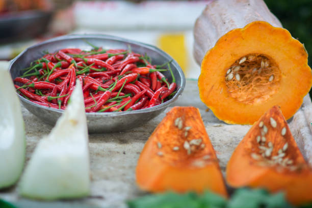 Red chilli peppers in a metal bowl, next to a sliced Cucurbita moschata