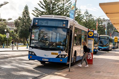 Sydney NSW Australia - May 27th 2020 - A bus parked at Bus Terminal and a young commuter approaching the driver for information at Coogee Beach on a sunny autumn afternoon