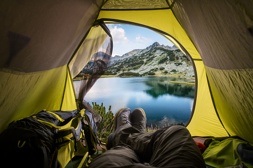 View of the lake and mountains through the open window of the tent. Sport and active life concept.
