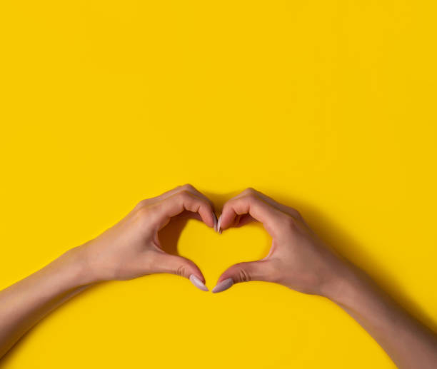 istock heart making woman's hands with manicure on yellow background, top view,banner 1249341272