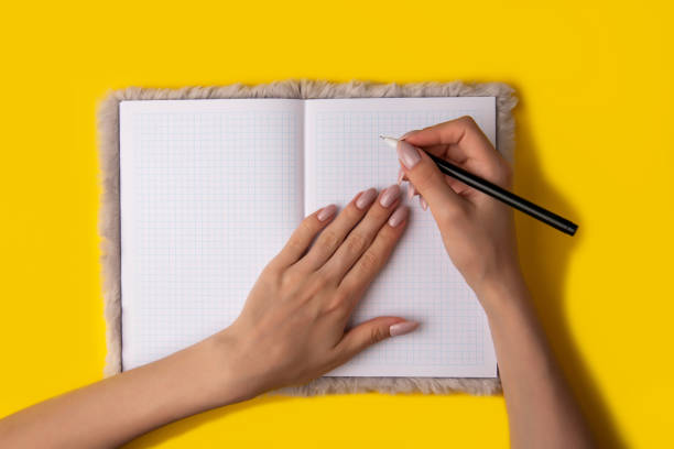 istock young woman hands hold opened notebook pages with black pen on yellow background 1249341329
