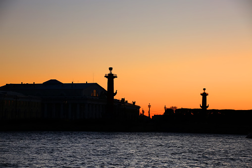 The Rostral Columns and the Old Saint Petersburg Stock Exchange buildings in silhouette at sunset, which are situated on Strelka, the eastern tip of Vasilievsky island, St Petersburg, Russia.