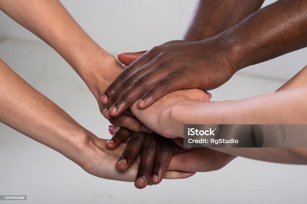 Anti racist studio shot of unrecognizable group of people holding hands Anti racist, anti discrimination studio shot of  unrecognizable, mixed race three people holding hands together. Anti-racism Stock Photo
