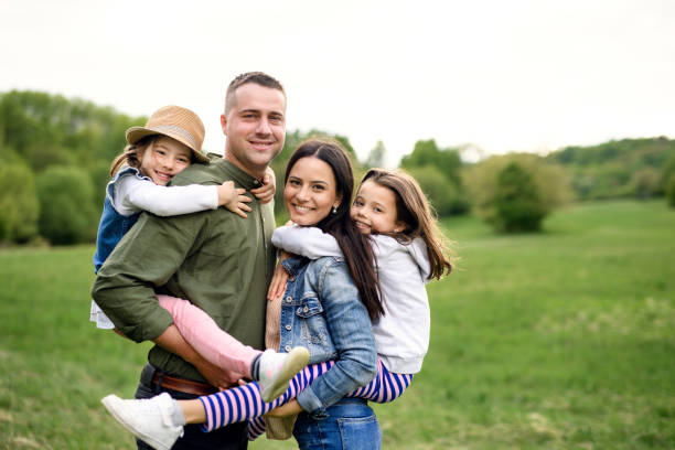 istock Happy family with two small daughters standing outdoors in spring nature. 1249348063