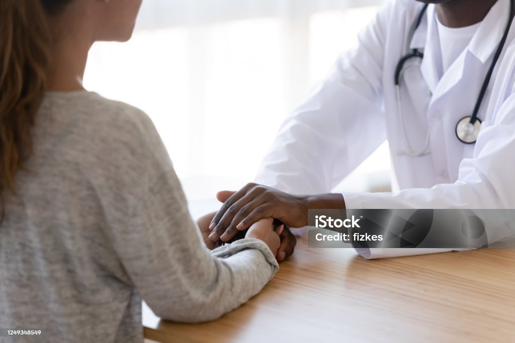 Close up of biracial doctor show support to female patient Crop close up of african American doctor hold female patient hands support after unsuccessful ivf procedure, caring biracial gynecologist show empathy comfort unhappy woman visitor after miscarriage Miscarriage Stock Photo