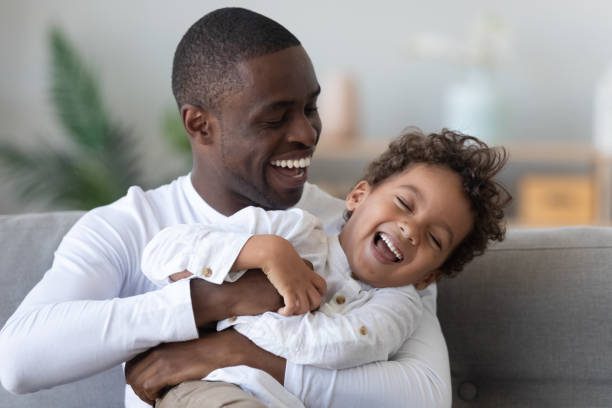happy ethnic dad and little son have fun at home - tickling imagens e fotografias de stock