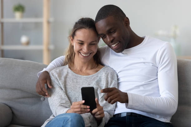 istock Happy international couple relax on couch using cellphone together 1249348587