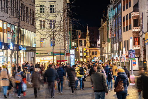 Nighttime view of pedestrian mall with crowded streets of people shopping, Leipzig, Germany